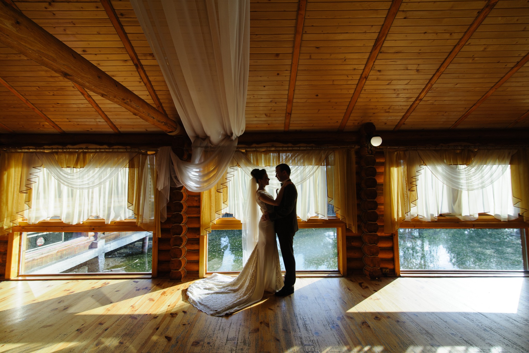 Silhouetted newlyweds inside a warm wood cabin