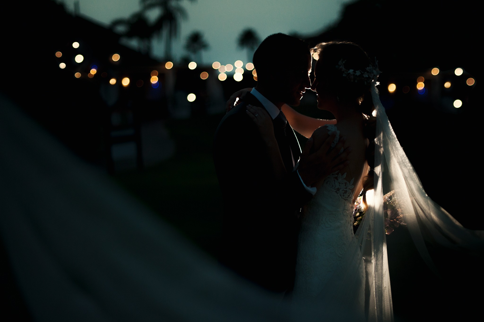 Wedding couple embracing beneath evening lights