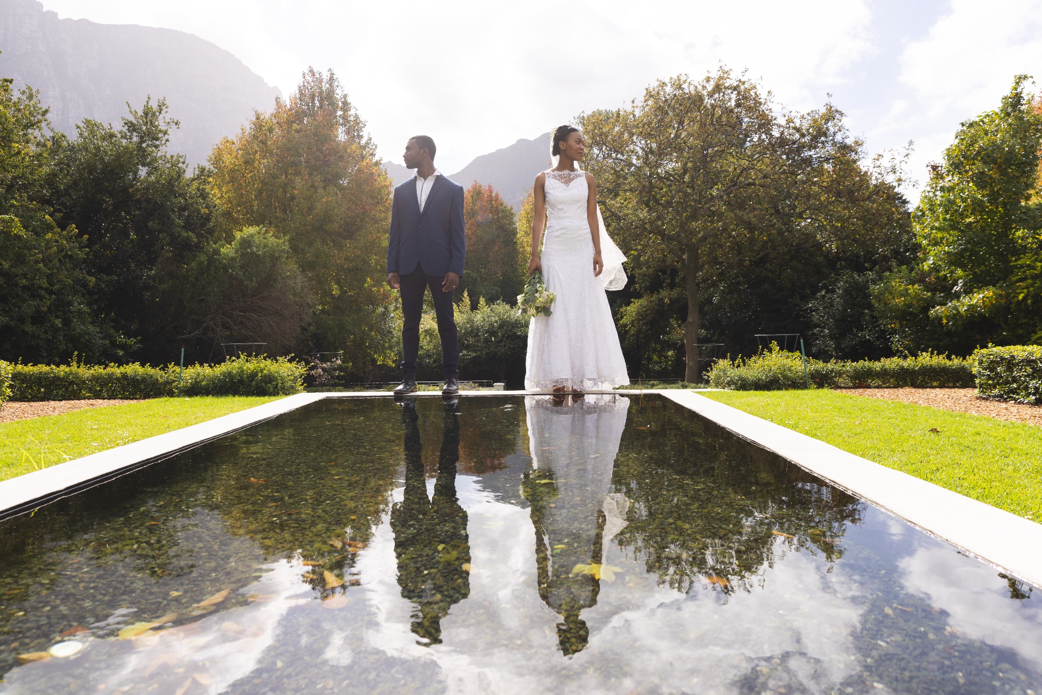 Newlyweds beside a reflective garden pool